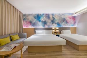 um quarto de hotel com duas camas e um sofá em 星程西安钟楼回民街酒店 em Xi'an