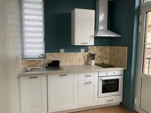 a kitchen with white cabinets and green walls at LE NID SUR LA FALAISE in Ault