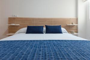 een slaapkamer met een groot bed met blauwe kussens bij Ag Aiguablava in Gandía