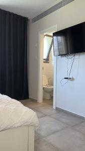 1 dormitorio con 1 cama y TV en la pared en דירת גן מהממת בבית שמש en Bet Shemesh