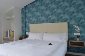 a bedroom with a large white bed with a blue wall at O Cabanel de Ali in Muxia