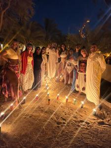 Al Kahina Gardens, Retreat and Resort في سيوة: مجموعة من الناس تقف على شاطئ به أضواء