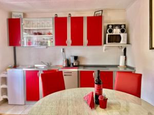 una cocina con armarios rojos y una mesa con una botella de vino en Kuća BORNA, en Crikvenica