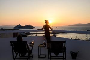 a woman standing on a balcony watching the sunset at She Mykonos - The Residency in Mýkonos City