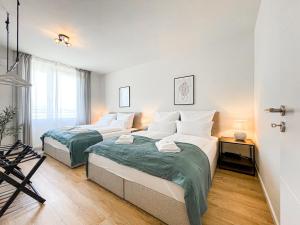 two beds in a large room with a window at E&K living - 6 pers - design apartment - fair - congress - parking in Augsburg