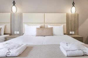 a bedroom with a large white bed with two towels on it at Aloni Hotel Pefkochori in Pefkohori