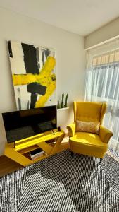uma sala de estar com uma cadeira amarela e uma televisão em Vytauto 80 em Palanga