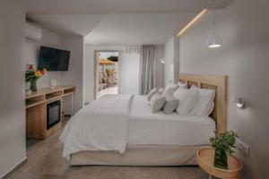 um quarto com uma grande cama branca com almofadas brancas em Anassa Suites Stalis by Estia "Adults Only" em Stalida