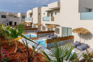 an external view of a hotel with a swimming pool and umbrellas at Anassa Suites Stalis by Estia "Adults Only" in Stalida