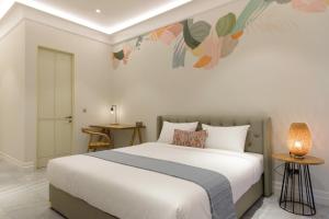 a bedroom with a large white bed and a table at CASA LIVING SENOPATI in Jakarta