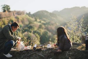 a man and woman sitting on a hill with a picnic at 暮らす実験室 in Taketa