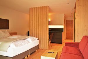 una camera con un letto e un divano rosso di Kastelart - Karbon a Castelrotto