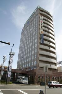 a tall building with cars parked in front of it at Hotel Route-Inn Chitose Ekimae in Chitose