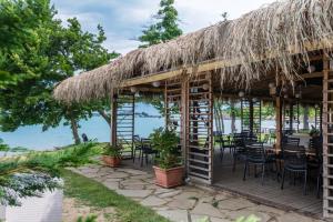 a restaurant with a thatched roof and tables and chairs at Viva Mare Beach Hotel by Santa Marina in Sozopol