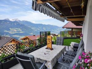 a table and chairs on a balcony with mountains at Ferienwohnung Zillertalblick in Stummerberg