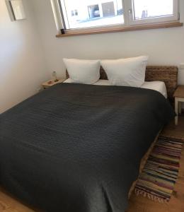 a bedroom with a black bed with two pillows and a window at Klosterblick - Inzigkofen (FeWo mit Naturteich) in Inzigkofen