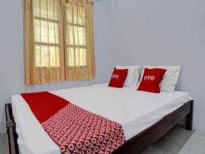 een bed met twee rode kussens erop bij OYO 92429 Vania Guest House in Medan