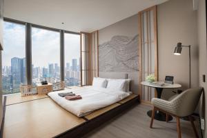 um quarto de hotel com uma cama, uma secretária e uma janela em UrCove by HYATT Shenzhen Nanshan Science and Technology Park em Shenzhen