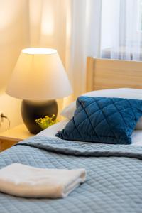 Bett mit blauer Decke und Lampe in der Unterkunft Bałuckiego Apartment Stary Mokotów Warsaw by Renters in Warschau