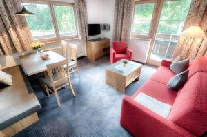 a living room with a red couch and a table at Appartement Désirée inkl der SUPER SOMMER CARD im SOMMER 2025 in Serfaus