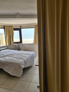 a bedroom with a bed and two windows at luxurious apartment with sea view in Blankenberge