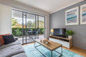 a living room with a couch and a tv and a table at MikaLex - Walking distance from the beach! in Nelson Bay