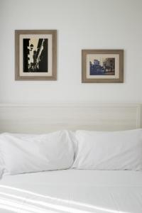 un letto bianco con due immagini incorniciate sopra di esso di Hotel Cantoria a Firenze