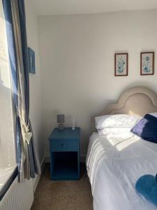 um quarto com uma cama e uma mesa de cabeceira azul com uma mesa azul em Assembly Cottage em Pocklington