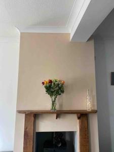 a vase of flowers sitting on top of a fireplace at Assembly Cottage in Pocklington