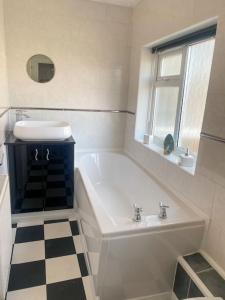 a bathroom with a white tub and a sink and a window at Assembly Cottage in Pocklington