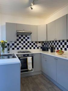 uma cozinha com armários brancos e azulejos pretos e brancos em Assembly Cottage em Pocklington