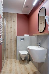 a bathroom with a sink and a toilet and a mirror at Apartamenty Albatros in Augustów