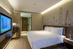 a hotel room with a bed and a tv at UrCove by HYATT Futian CBD in Shenzhen