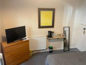 a bedroom with a tv on a dresser with a dresser at Holbury B&B in Southampton