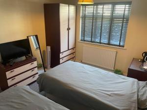 1 dormitorio con 2 camas y TV de pantalla plana en Holbury B&B en Southampton