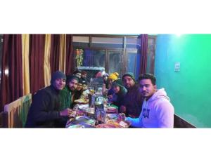 een groep mensen die rond een tafel zitten met eten bij Anjali Homestay, Ukhimath in Ukhimath