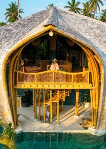 una mujer sentada en una terraza junto a una piscina en Villa Tokay - Luxury Private Villas, en Gili Air