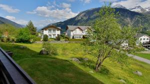 ein Haus auf einem Feld mit Bergen im Hintergrund in der Unterkunft Apart Holidays - Haus Acletta in Disentis