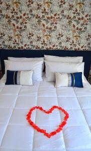 un letto bianco con un cuore rosso sopra di Kairos Suite a Modugno