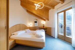 a bedroom with a bed with white sheets and a window at PENSION KLUGHAMMER in Caldaro