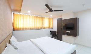 Habitación con cama y TV. en FabHotel The Heaven en Ahmedabad