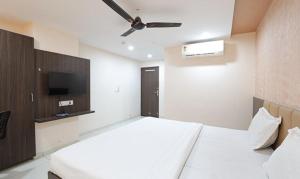 1 dormitorio con cama blanca y ventilador de techo en FabHotel The Heaven en Ahmedabad