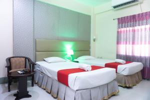 a room with two beds and a table and a chair at Hotel Golden Inn Chattagram Ltd in Chittagong