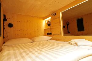 a bed in a wooden room with a mirror at Ljubljana Capsule Hostel in Ljubljana