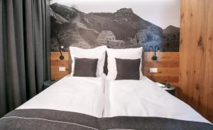 two white beds with black pillows in a bedroom at Landhaus Boutique Motel - contactless check-in in Nendeln