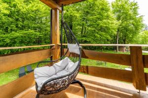 a porch with a swinging chair on a deck at B&B Plitvica Lodge in Plitvica selo