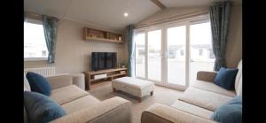 Charming 3-Bed Caravan in Colchester Mersea island في كولشستر: غرفة معيشة مع كنبتين وتلفزيون