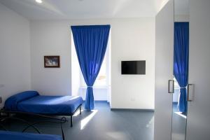 Zimmer mit 2 Betten und einem Fenster mit blauen Vorhängen in der Unterkunft Knight House in Neapel