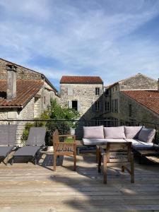 a patio with a couch and two chairs on a deck at Le Clos des Grands Frênes in Pons