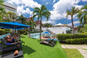 a resort with a pool with people laying on chairs and umbrellas at Phunawa Resort Phuket Karon Beach - SHA Plus in Karon Beach